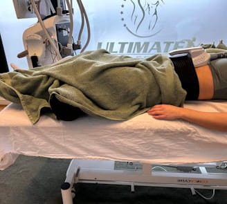 kvinde ligger på ryg og modtager em body sculpting behandling
